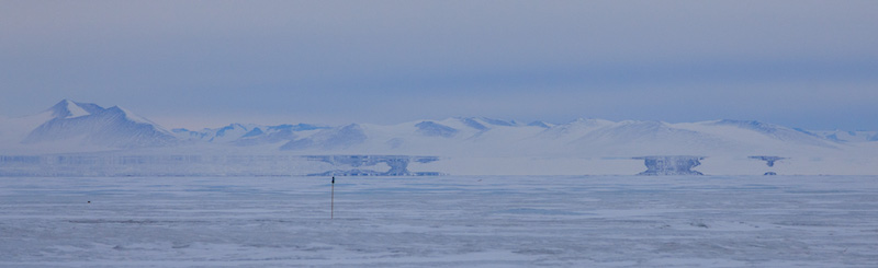 Fata morgana at the base of the Transantarctic Mountains. In this photograph the fata morgana mirage appears just above the base of the mountains and you can see it most clearly as a mirror image of the bare rock in the center of the photograph as well as on the right side of the image. 