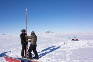 Mike and Baptiste drilling the firn core at Summit Camp - the Big House is in the background. 