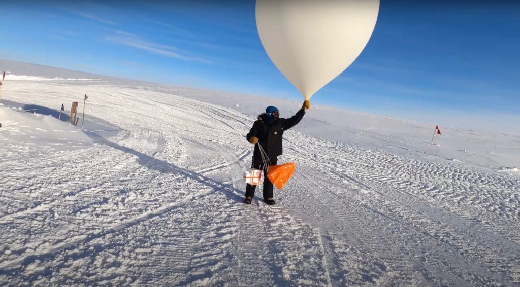 A scientist launching a weather balloon carrying ozone-measuring instruments from the South Pole Station.